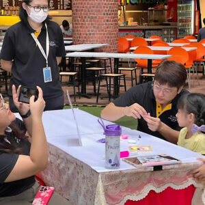 Image of Plaza Premium Group employees interacting with a child taking part in a painting activity