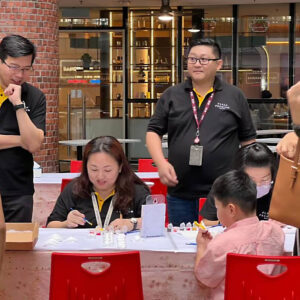 Image of Plaza Premium Group employees interacting with a child taking part in a painting activity