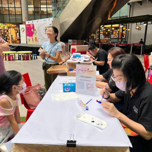 Image of Plaza Premium Group employees interacting with a child taking part in a painting activity